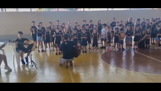 Claudinho tocando para uma plateia de crianças num ginásio